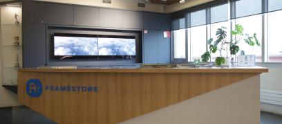 a modern reception area, there is blue lettering on the wooden desk that says "Framestore"